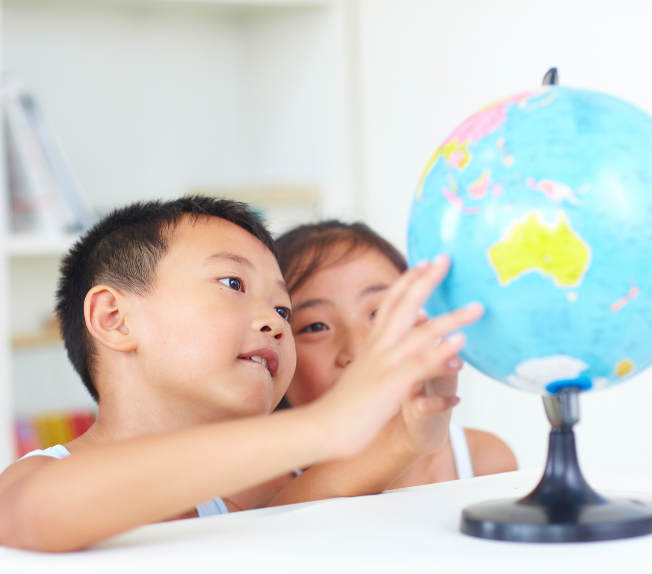 two kids study globe together